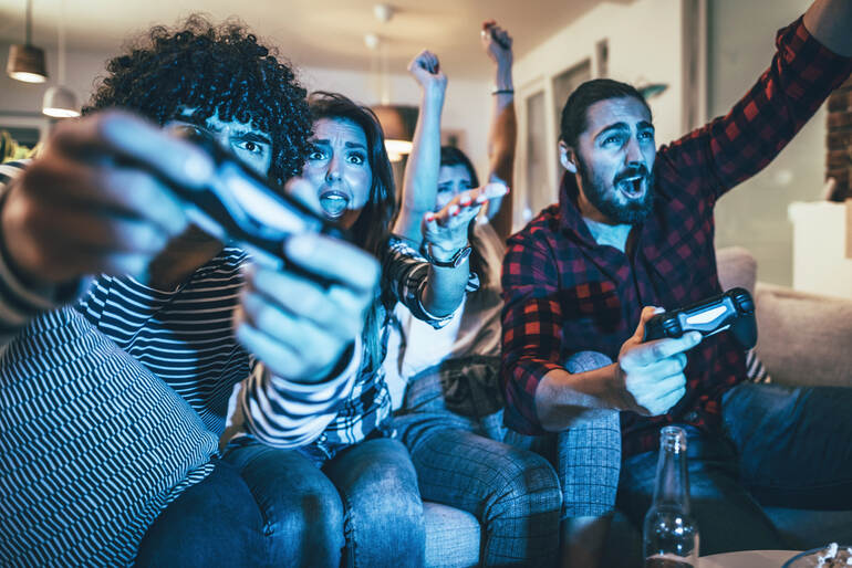 A group of friends playing video games while drinking beers