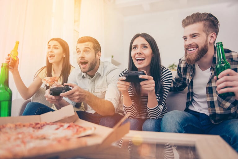 A group of friends drinking beer, eating pizza, and playing video games during a casual beer game night.