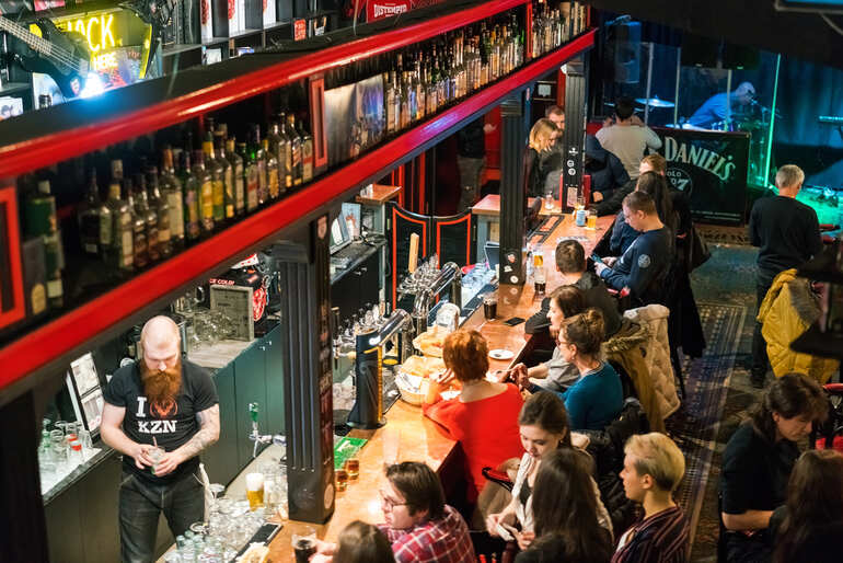 Busy bar counter with individuals drinking in one of the best pubs in the world.