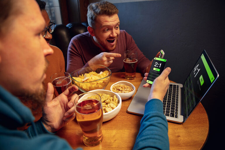 Friends enjoying online casino gaming while drinking craft beer at home