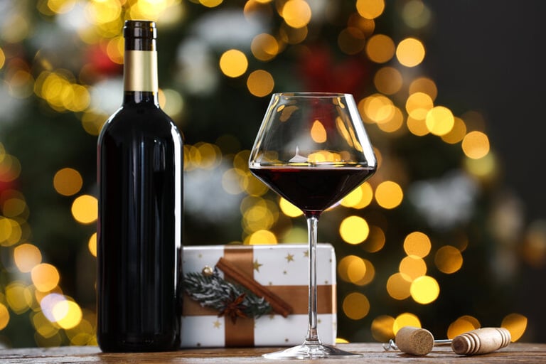 Holiday gift scene with a bottle and glass of red wine, a wrapped present, and festive lights for wine lovers.