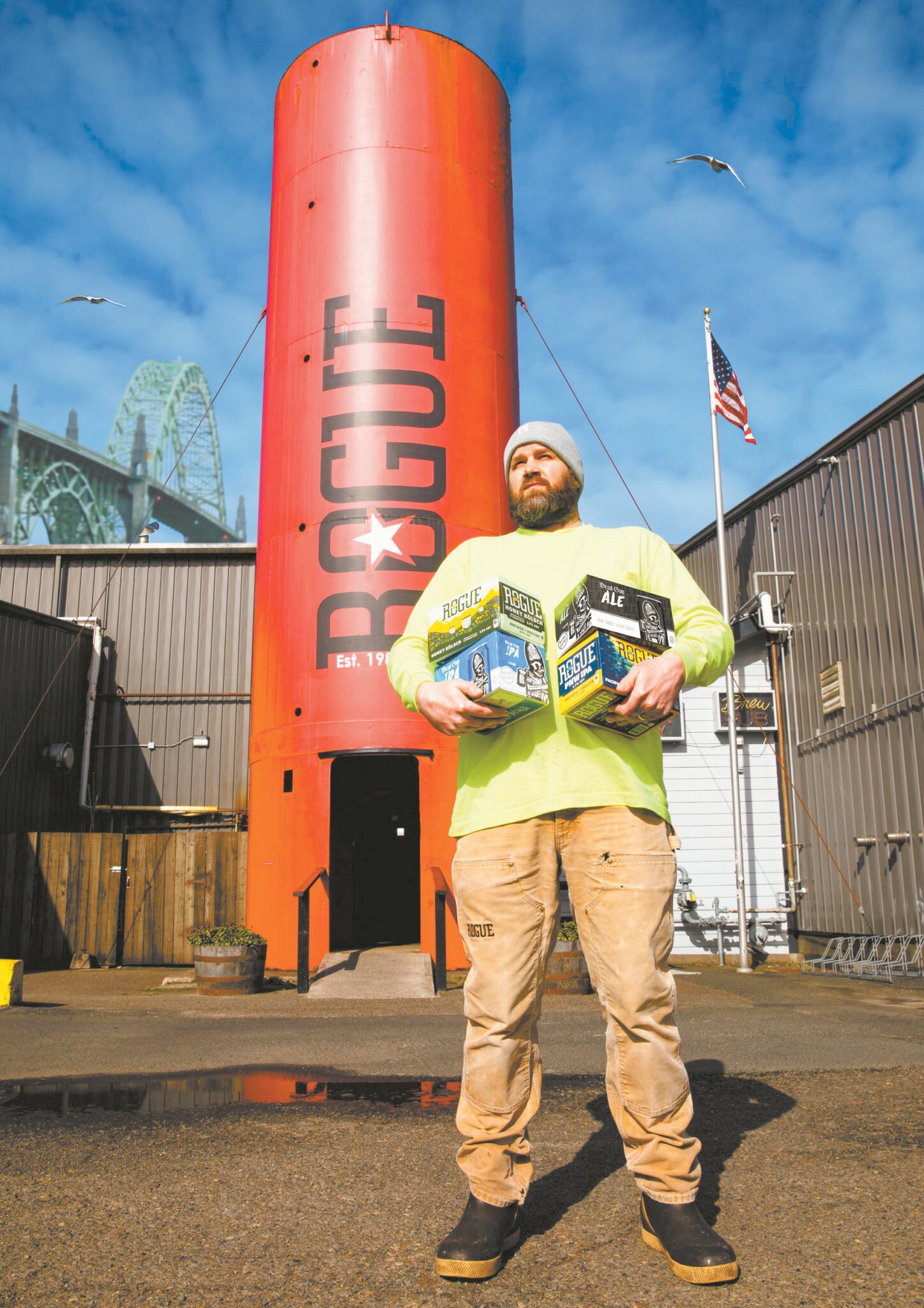 Man holding Rogue beer in front of Rogue Brewery