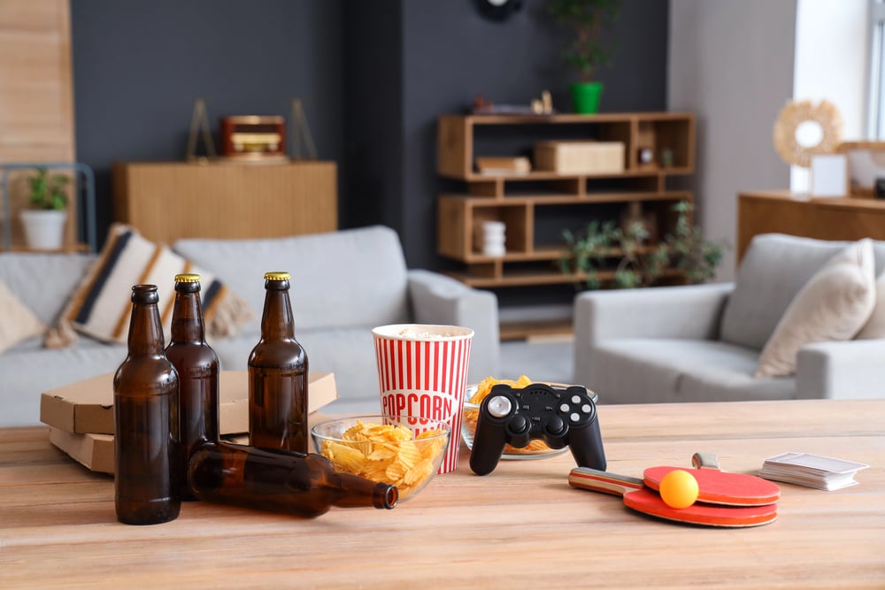 Beer bottles with snacks, a game controller, and a paddle ball on the table.