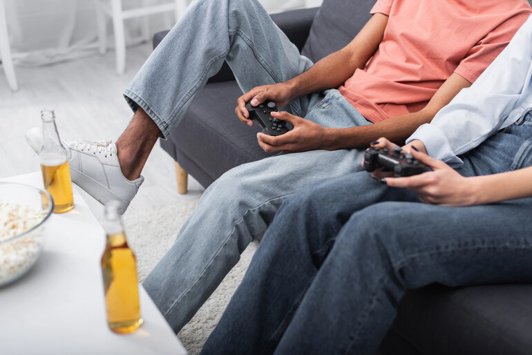 Gamers relaxing on a couch while playing video games and drinking beer during a long gaming session