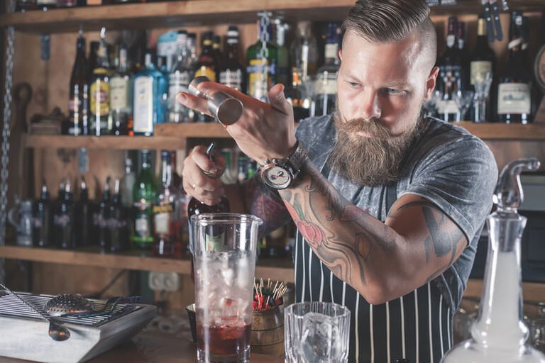 Bartender crafting a cocktail behind the bar, representing turning a passion for drinks into a professional career.