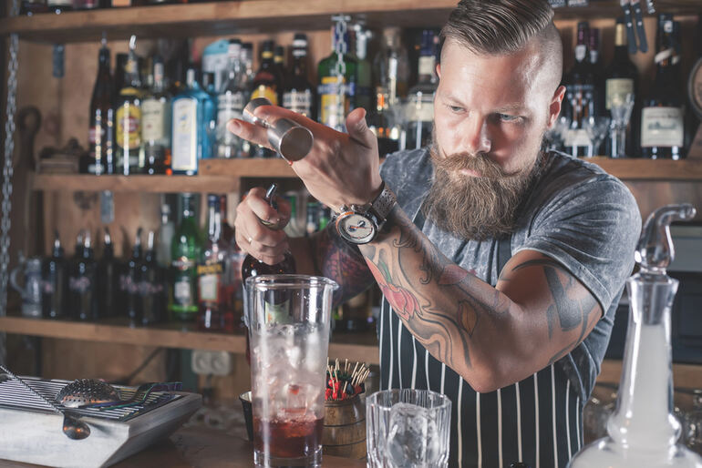 Bartender crafting a cocktail behind the bar, representing turning a passion for drinks into a professional career.