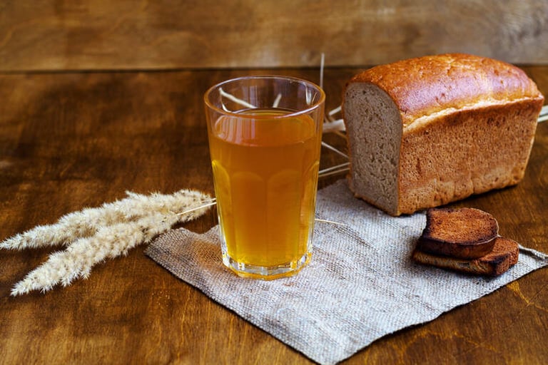A glass of beer with artisan bread on a wooden table