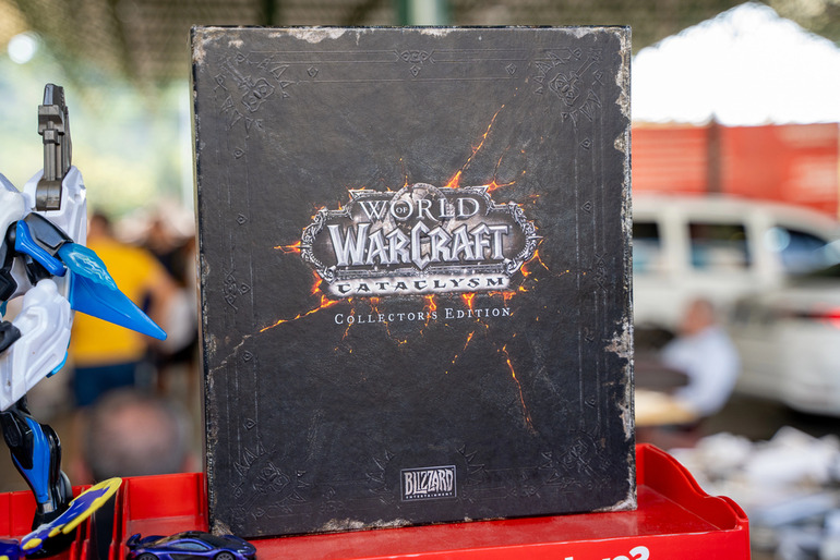 Laptop showing World of Warcraft character screen on a desk with mini figures and a mug