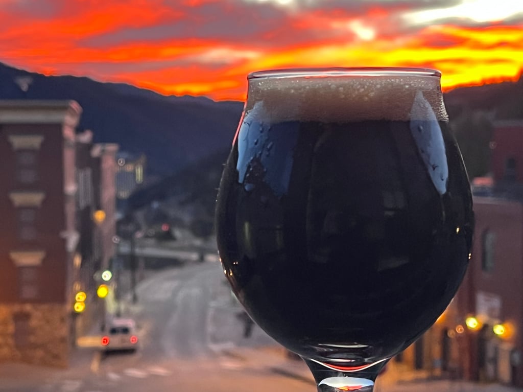 Beer glass with sunset and mountains in the background.