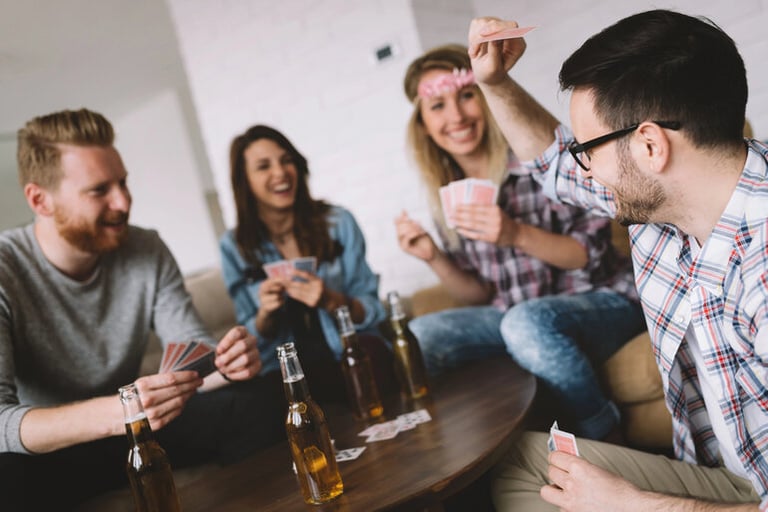 Friends enjoying craft beers while playing cards together during a fun game night