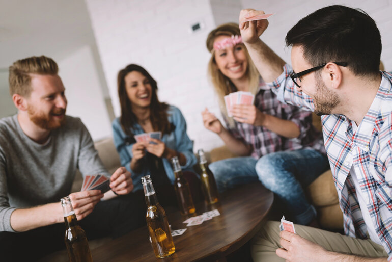 Friends enjoying craft beers while playing cards together during a fun game night