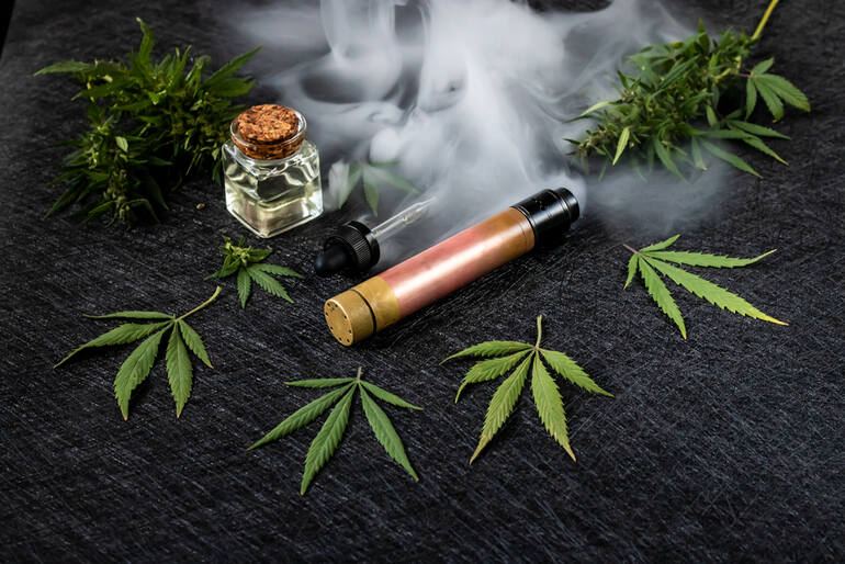 THC vape pen with cannabis leaves and oil, showing vape juice vs flower comparison