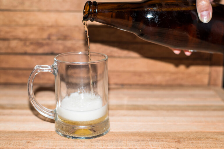 Person pouring beer into a glass mug, representing balanced wellness and mindful drinking habits for beer lovers