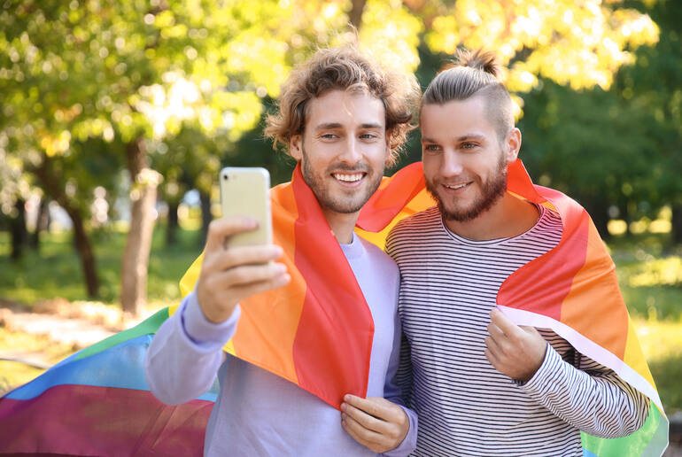 A couple taking a selfie with a rainbow flag, showing LGBTQ+ connection