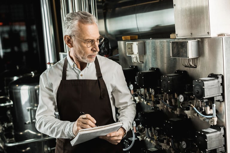 Worker monitoring industrial brewing process with notes