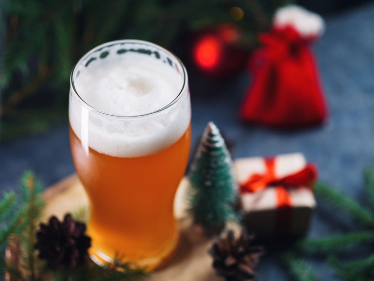 Glass of beer on a wooden table with festive Christmas decorations, seasonal winter warmer beer themed alongside an NBA viewing atmosphere