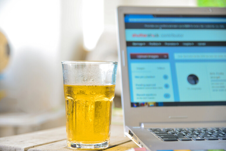 A glass of craft beer beside a laptop displaying an online prediction market