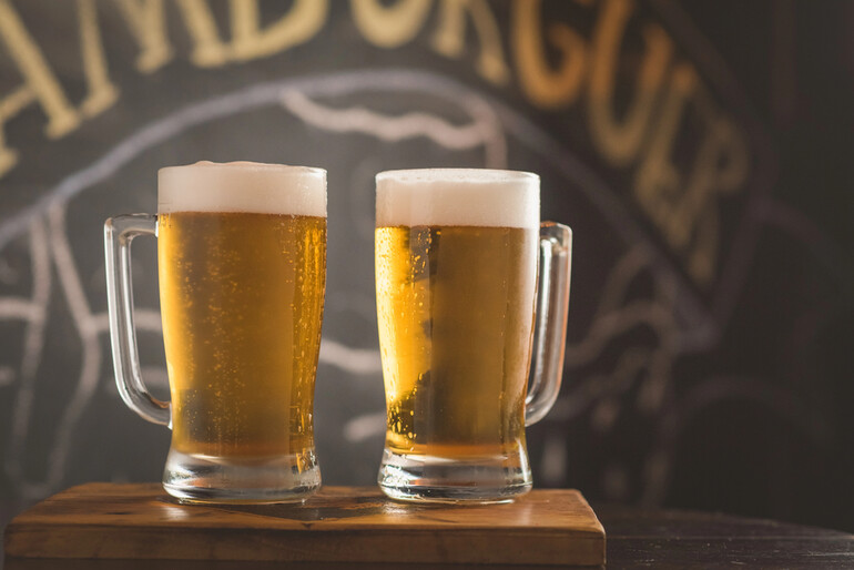 Two beer mugs displaying Australian beer products in a pub environment.