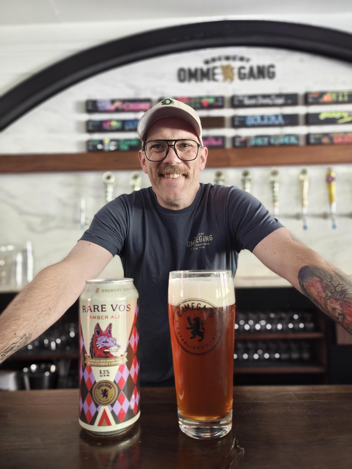 Man leaning over can and glass of Rare Vos