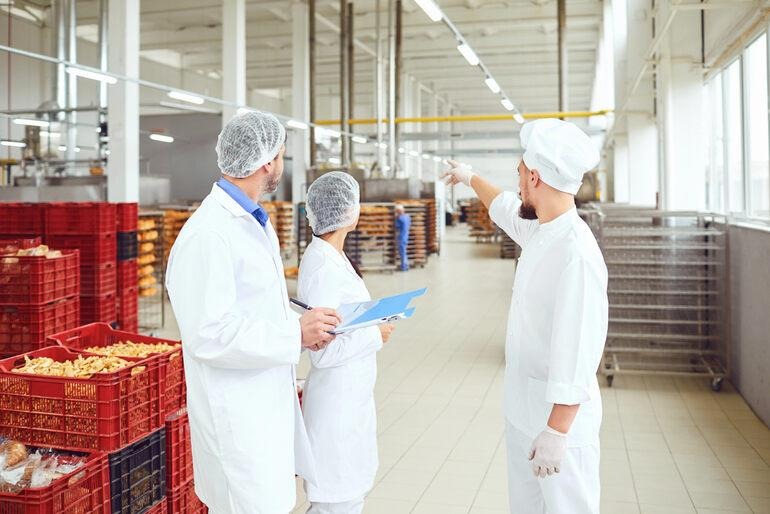 Food manufacturing team reviewing production line operations to improve maintenance efficiency and workflow.