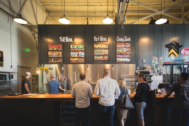 Several Customers standing in front of a tap list at a bar
