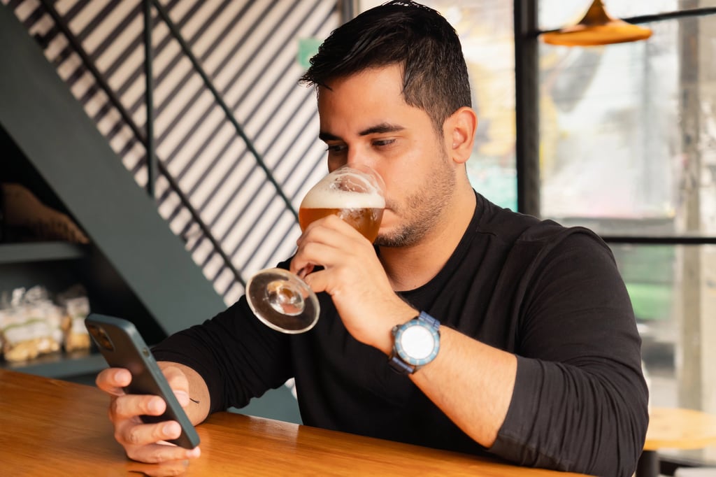 Man rating beers on his phone while he sips a pint.