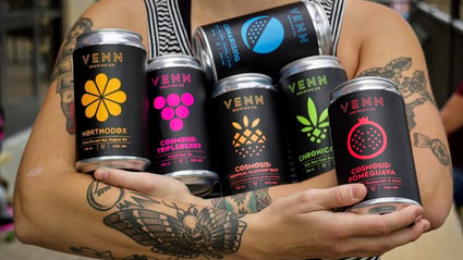 Venn Brewing collection of cans being cradled by a brewery worker.