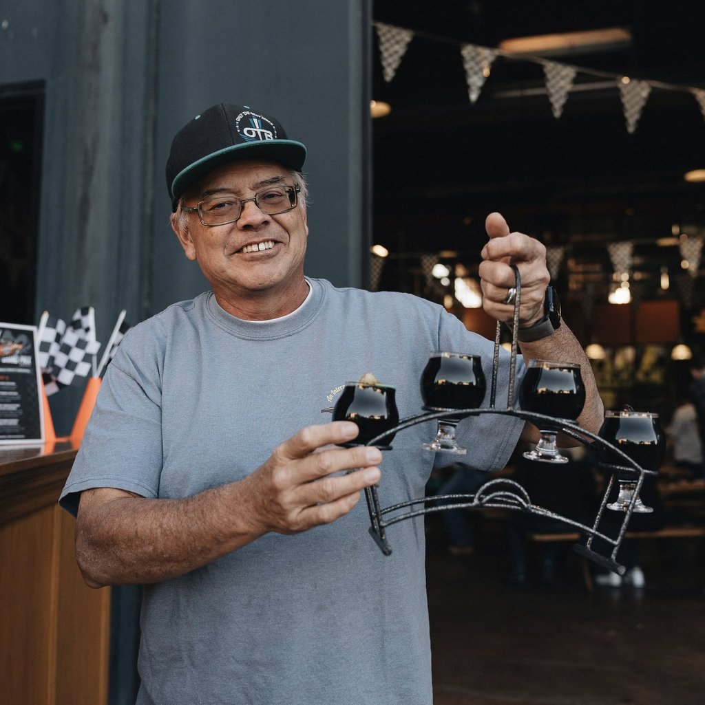 Man holding interesting flight of AleSmith Speedway Stout.