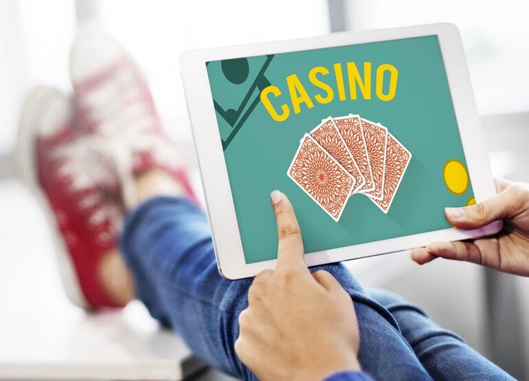 Person using a tablet with an online casino game, highlighting the need to read terms and conditions before signing up in New Zealand.