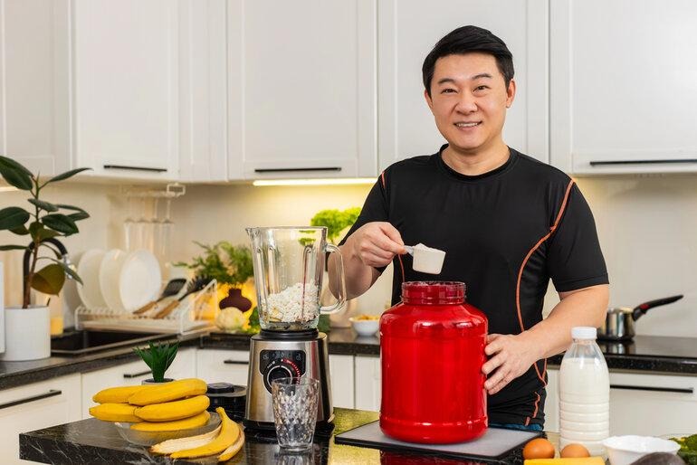 Person preparing a creatine protein shake in a kitchen, representing creatine beverage co-packer selection.