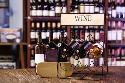 Wine bottles displayed on a retail rack in a specialty wine and beverage store, representing inventory management and product organization.