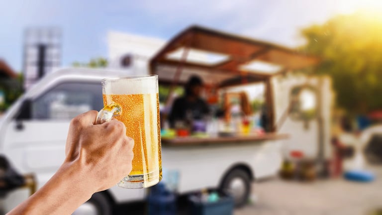 Mobile beer truck serving customers with a fresh pint of beer outdoors.