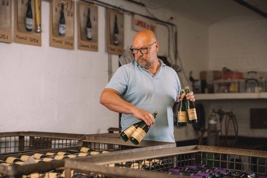 Hanssens brewer with bottles of Oude Kriek and Oude Gueze.