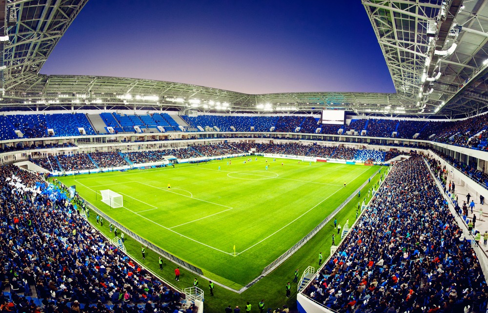 Multifunctional sports arena hosting a football match and large crowds.