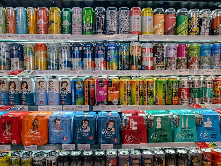 Colorful craft beer cans with eye-catching labels displayed on a store shelf.