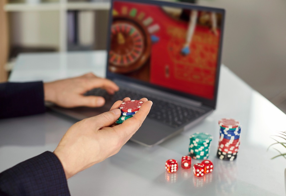 A man playing online casino, holding poker chips.