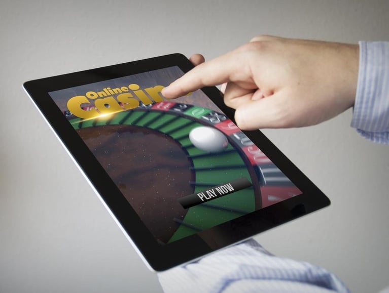 A man points a finger at a tablet with an online casino on screen.