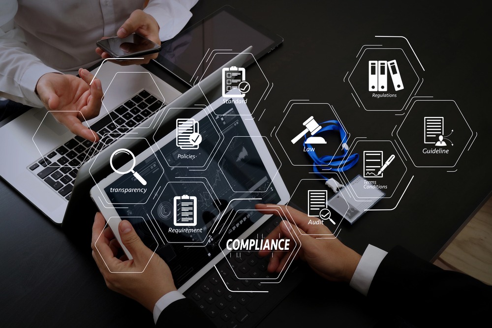 A tablet with digital icons representing business compliance, regulations, law, and corporate policies overlaid on the screen.