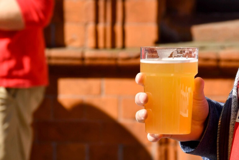 A hand holding a glass of beer.