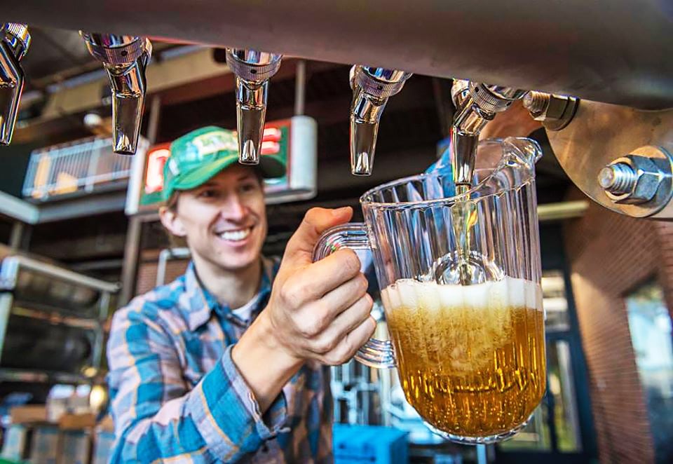 happy bartender pouring beer from a tap