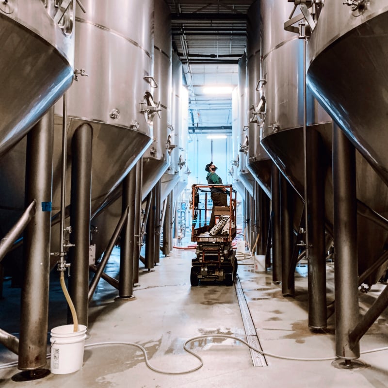 uinta brewer checks on a fermentation tank