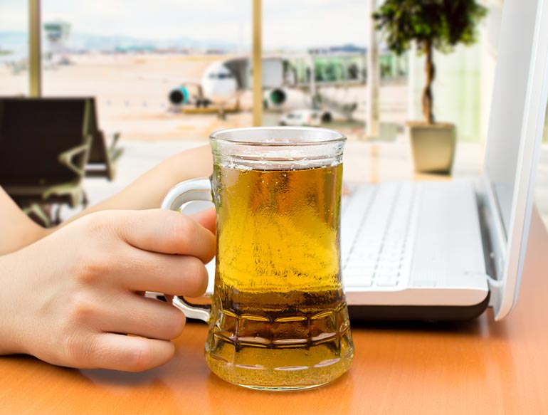 person holding mug of beer while working at airport with airplane in background