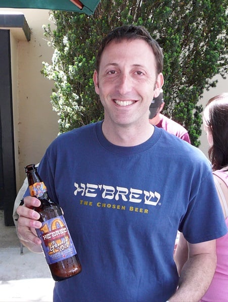 Jeremy Cowan holding a bottle of "10" from Shmaltz Brewing.