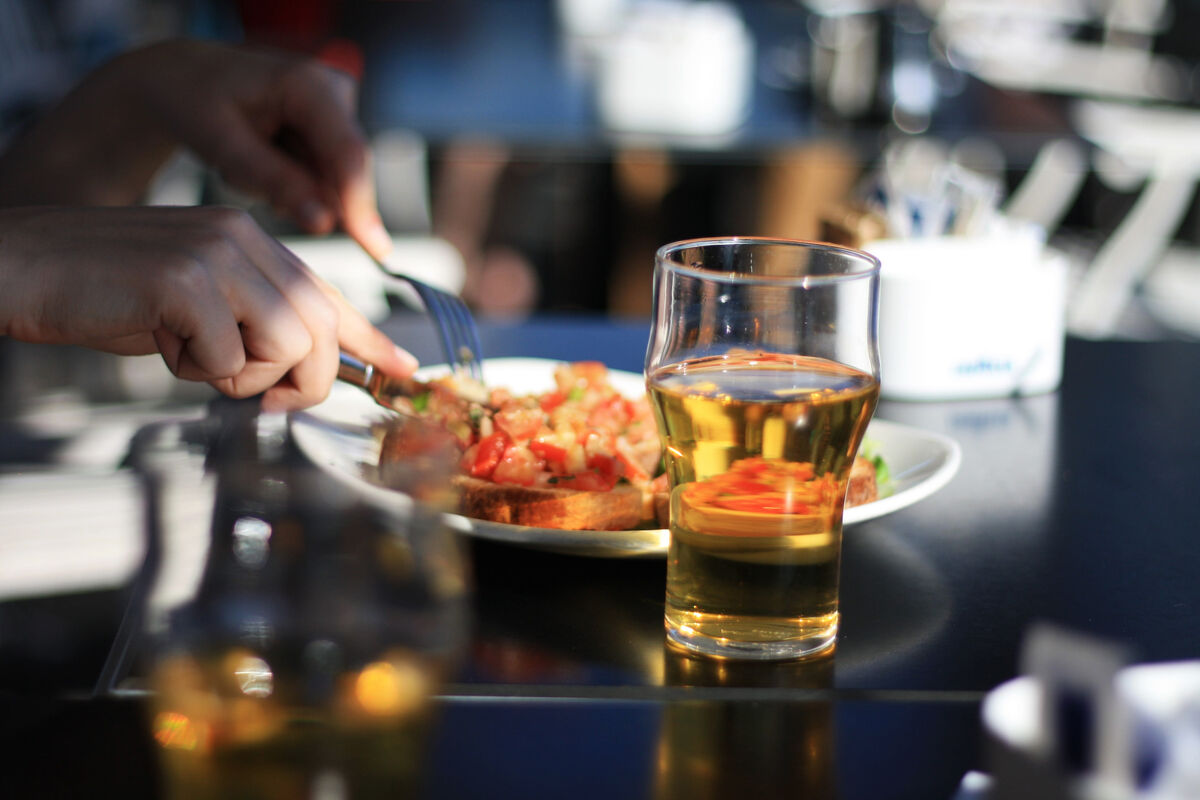 person eating food with beer next to plate