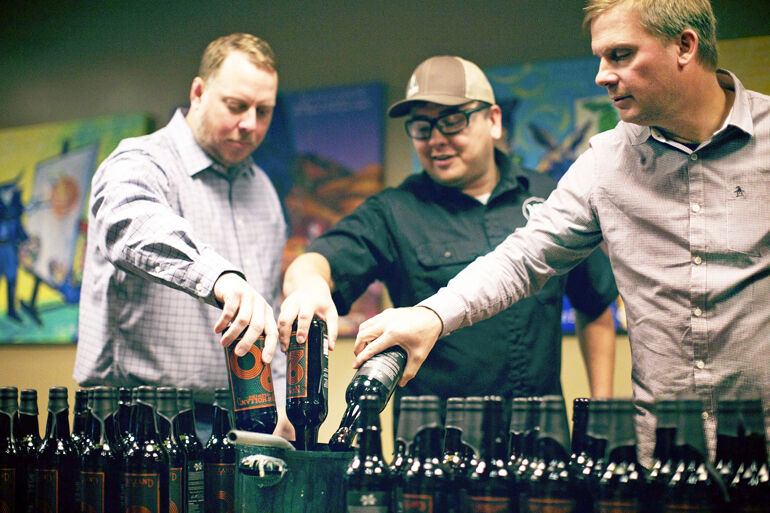 Partner David White (left) with Brewery Production Manager Jason Salas (middle) and Brett VanderKamp dipping 20th Anniversary bottles into wax.