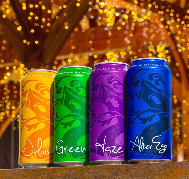 cans of tree house julius, haze, alter ego and green underneath a well-lit patio at the brewery