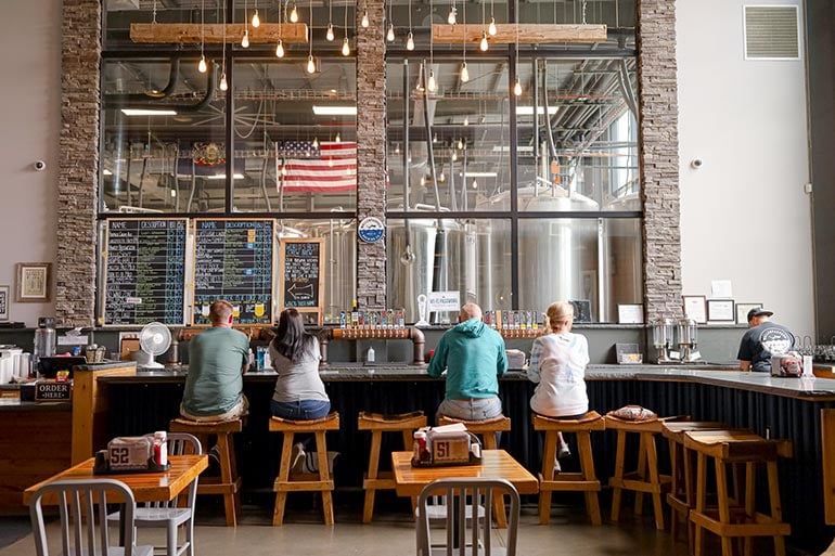 wallenpaupack brewing taproom with fermentation tanks visible behind glass