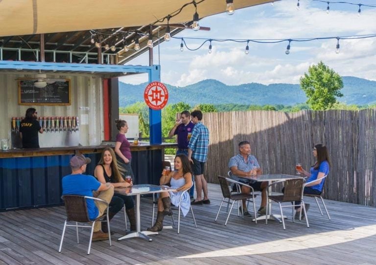 Group of happy people enjoying the sunny outdoor patio at Highland Brewing Co.