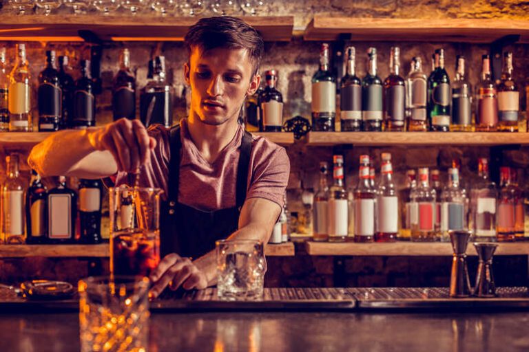 A bartender preparing a cocktail in a bar where beer and gambling go hand-in-hand