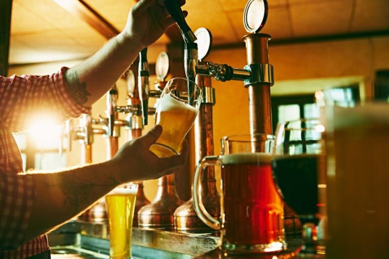 A bartender pouring a fresh craft beer from a tap at a modern brewery